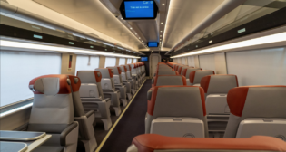In the new Acela trainsets, the color “red” distinguishes First Class from Business Class—as evident in the headrests here, and also on the door to the trainset. These First Class seats provide more space and leg room as well as personal tray tables, according to Amtrak. (Photo Courtesy of Amtrak)