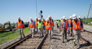 NTSB Chair Homendy and NTSB investigators, along with investigation party members, walk the accident scene of the June 27 grade crossing collision and derailment between an Amtrak passenger train and dump truck near Mendon, Mo. (Photograph and Caption Courtesy of NTSB, via Twitter, June 29)
