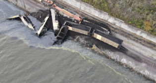 ​Aerial photo of the derailment of the two locomotives and eight hopper cars. Two additional hopper cars are submerged in the river. (Source: BNSF)​
