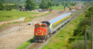 A CN train is viewed passing the Milton Intermodal Terminal construction site in July 2023 as crews work to extend the "CN Ash" control point in preparation for the Terminal. The train pictured is CN delivering a new Siemens Venture trainset to VIA Rail in Montreal. (Caption and Photograph Courtesy of Stephen C. Host)