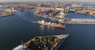 Aerial view of container cargo ship leaving Long Beach Harbor in Los Angeles County California. (Port of Long Beach photo)