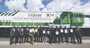 FRA Administrator Amit Bose, Anacostia Rail Holdings executives, and ports of Los Angeles and Long Beach officials on May 4, 2023, gathered to celebrate PHL’s latest group of locomotive engineer graduates to serve the San Pedro Port complex. They stand in front of Progress Rail’s zero-emission EMD® Joule battery-electric locomotive. Since this photograph was taken, PHL has been operating the locomotive for one year. (Photograph Courtesy of The Wolcott Group)